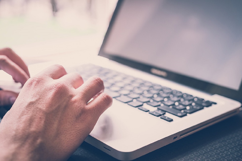 Un ordenador portátil y unas manos escribiendo sobre el teclado