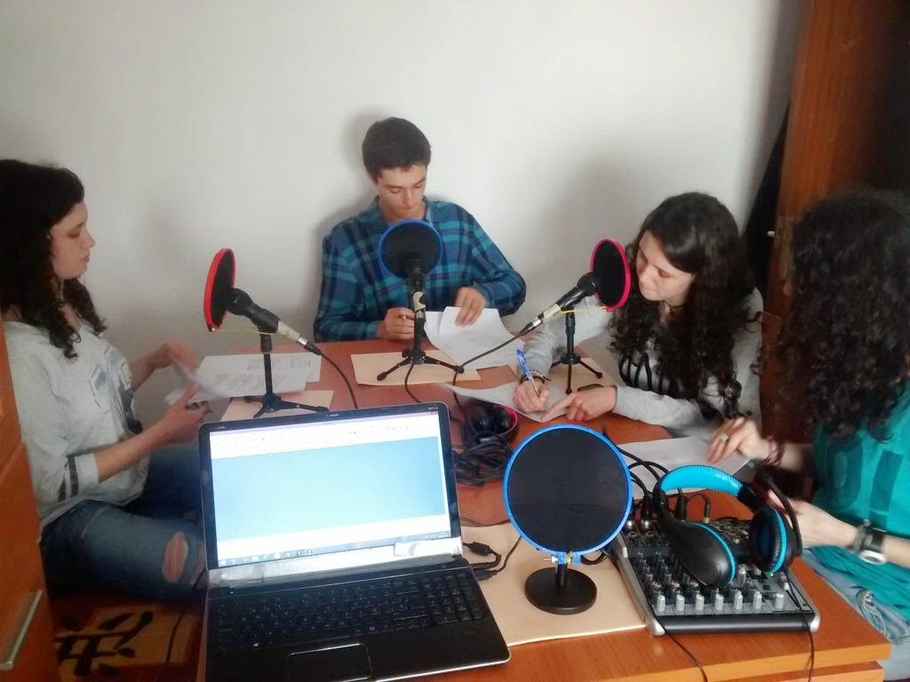 Cuatro chicos en una mesa con equipo para grabar podcasts